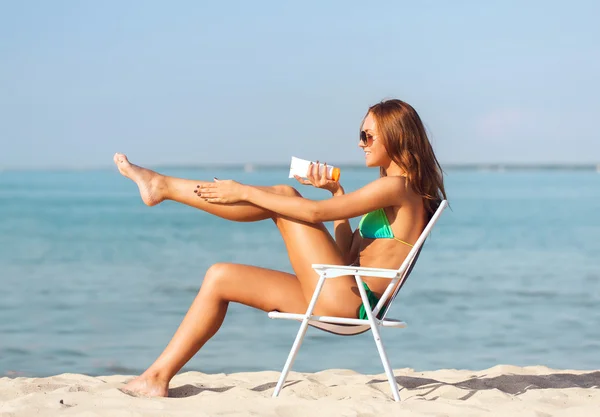Smiling young woman sunbathing in lounge on beach — Stock Photo, Image