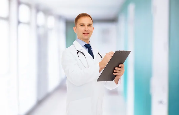 Улыбающийся врач с планшетом и стетоскопом — стоковое фото