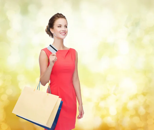 Femme souriante avec sacs à provisions et carte plastique — Photo