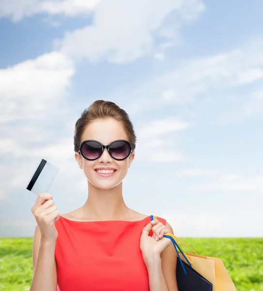 Femme souriante avec sacs à provisions et carte plastique — Photo