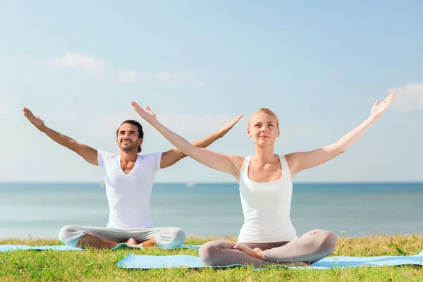 Çift gülümseyen açık havada yapım yoga egzersizleri — Stok fotoğraf