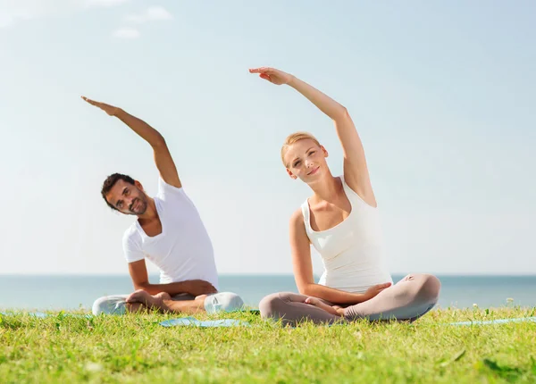 Cuplu zâmbind făcând exerciții de yoga în aer liber — Fotografie, imagine de stoc