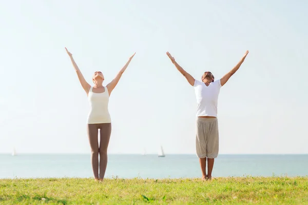 Glimlachend paar oefeningen maken yoga buiten — Stockfoto