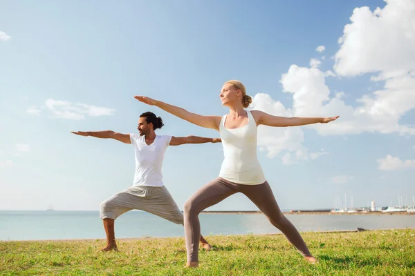 Çift gülümseyen açık havada yapım yoga egzersizleri — Stok fotoğraf