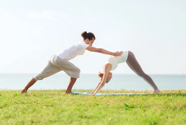 Pareja sonriente haciendo ejercicios de yoga al aire libre —  Fotos de Stock