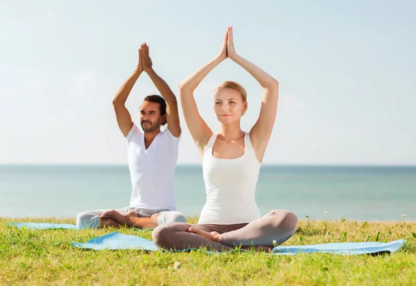 Çift gülümseyen açık havada yapım yoga egzersizleri — Stok fotoğraf