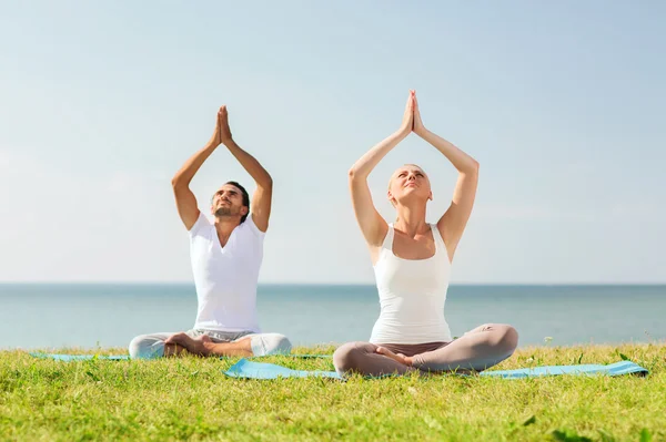 Glimlachend paar oefeningen maken yoga buiten — Stockfoto