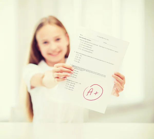 Улыбающаяся маленькая студентка с тестом и оценкой — стоковое фото