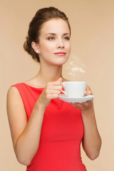Mulher sorridente em vestido vermelho com xícara de café — Fotografia de Stock