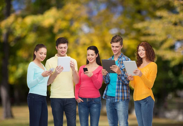 Grupo de adolescentes con teléfonos inteligentes y tableta PC — Foto de Stock