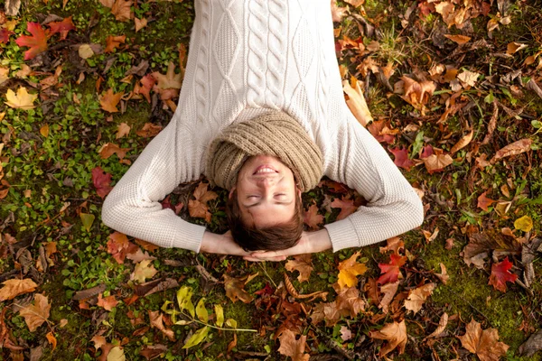 微笑年轻男子躺在地上，在秋天的公园 — 图库照片