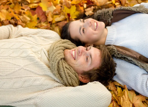 Close up of smiling couple lying in autumn park — Stock Photo, Image