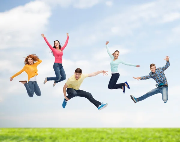 Gruppo di adolescenti sorridenti che saltano in aria Fotografia Stock