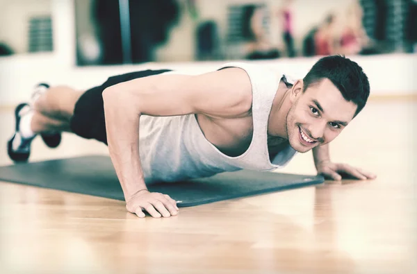 Uomo sorridente che fa flessioni in palestra — Foto Stock