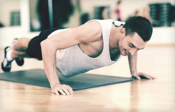 Χαμογελαστός άνθρωπος κάνει push-ups στο γυμναστήριο — Zdjęcie stockowe