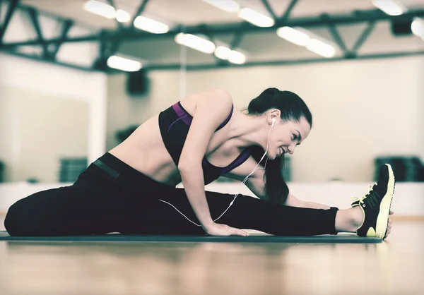 Smiling woman stretching on mat in the gym — Stock Photo, Image