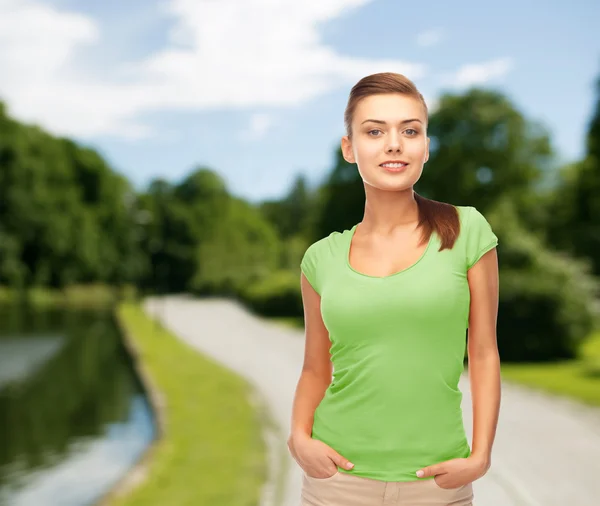 Улыбающаяся молодая женщина в пустой зеленой футболке — стоковое фото