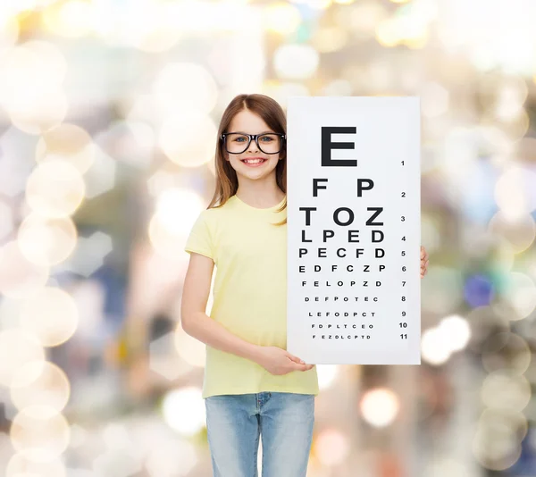 Little girl in eyeglasses with eye checking chart — Stock Photo, Image