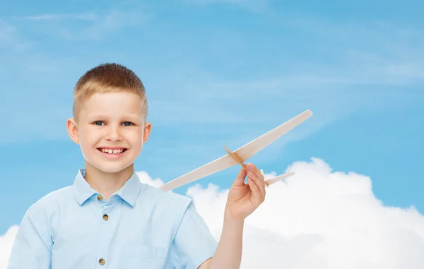 Niño sonriente sosteniendo un modelo de avión de madera — Foto de Stock