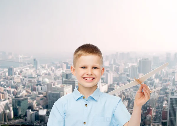 Küçük çocuk ahşap uçak model tutan gülümseyerek — Stok fotoğraf