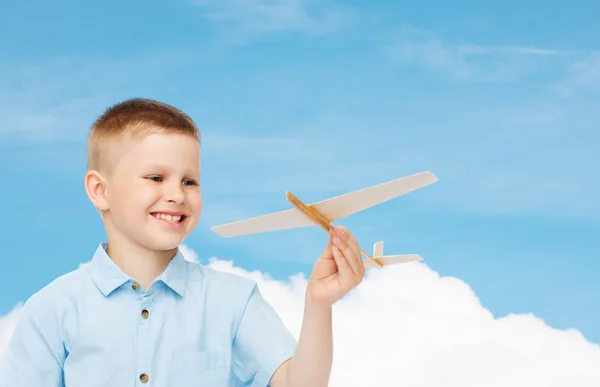 Menino sorrindo segurando um modelo de avião de madeira — Fotografia de Stock