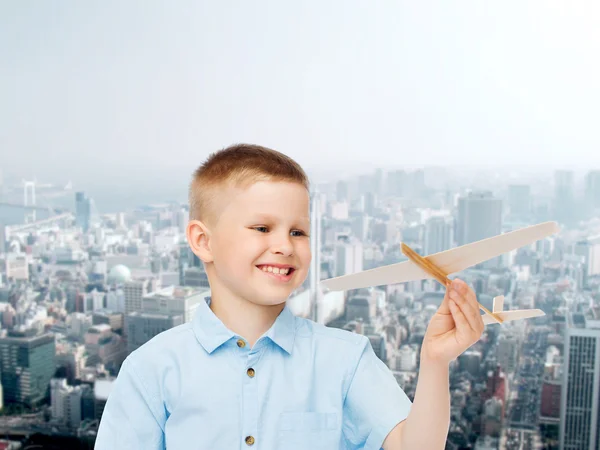 Menino sorrindo segurando um modelo de avião de madeira — Fotografia de Stock