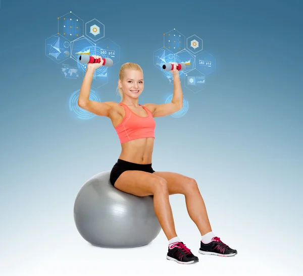 Woman with dumbbells sitting on fitness ball — Stock Photo, Image