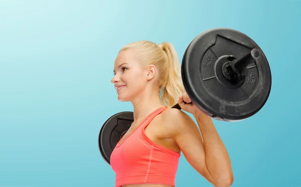 Sorrindo mulher desportiva exercitando com barbell — Fotografia de Stock