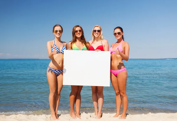 Group of smiling women with blank board on beach — Stock Photo, Image