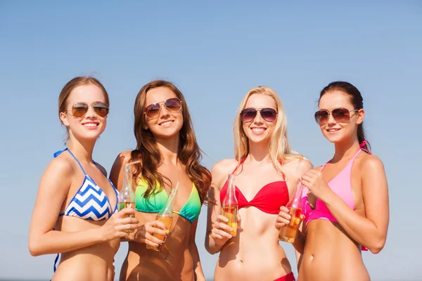 Группа улыбающихся молодых женщин, пьющих на пляже — стоковое фото
