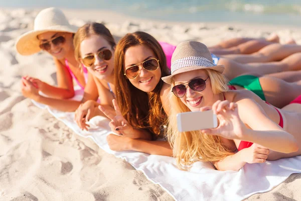 Grupo de mujeres sonrientes con teléfono inteligente en la playa — Foto de Stock