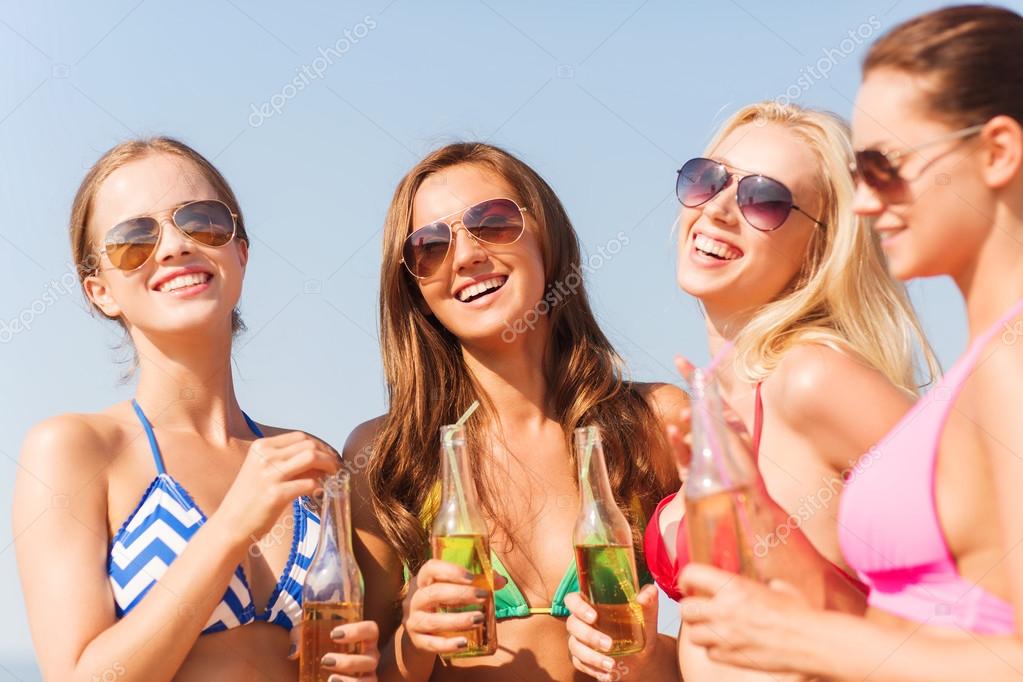 Groep van jonge vrouwen drinken op strand glimlachen — Stockfoto ...