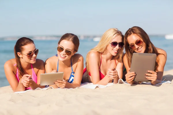 Grupo de mulheres jovens sorridentes com comprimidos na praia — Fotografia de Stock