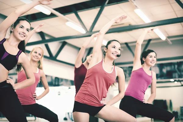 Groep glimlachende mensen die zich uitstrekt in de sportschool — Stockfoto