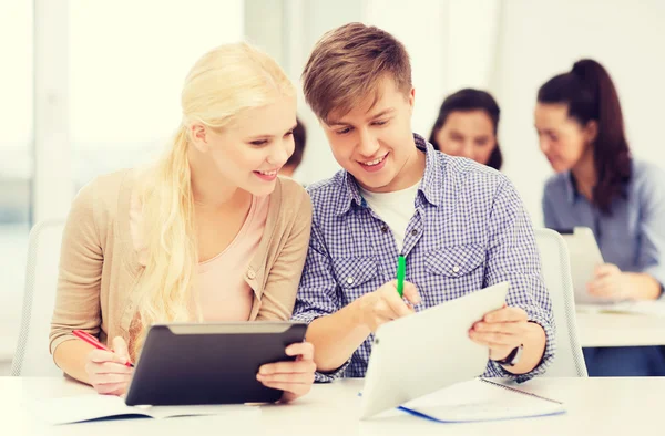 Twee lachende studenten met tablet pc en -laptops — Stockfoto