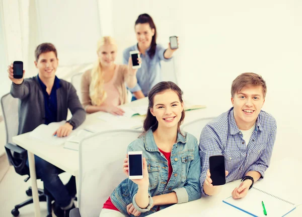 Studenti che mostrano schermi bianchi neri dello smartphone — Foto Stock