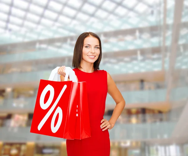 Alışveriş çantalı kırmızı elbiseli kadın. — Stok fotoğraf