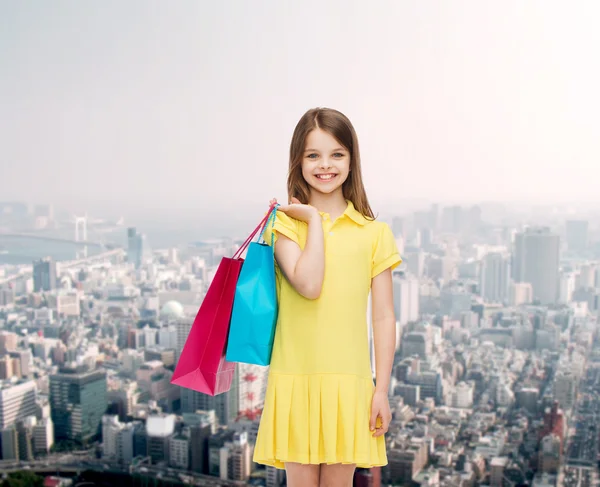 Lachende meisje in jurk met shopping tassen — Stockfoto