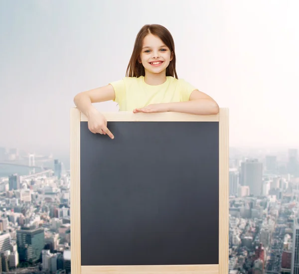 Happy little girl pointing finger to blackboard — Stock Photo, Image