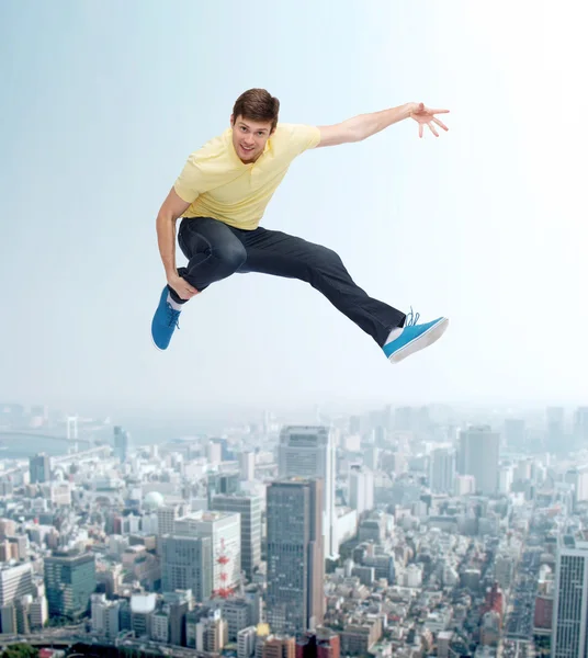 Smiling young man jumping in air — Stock Photo, Image