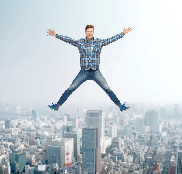 Smiling young man jumping in air — Stock Photo, Image