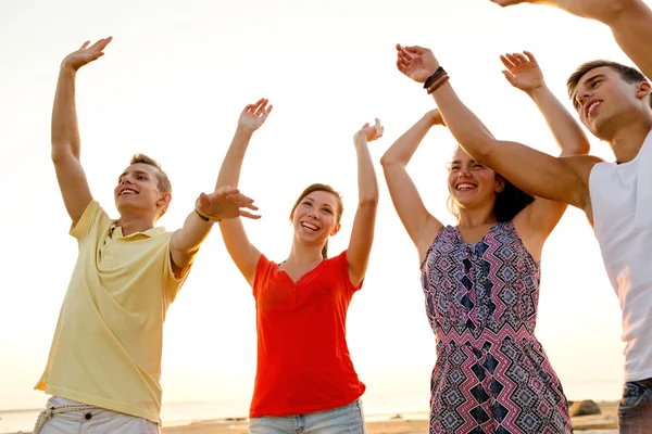 Amigos sonrientes bailando en la playa de verano — Foto de Stock