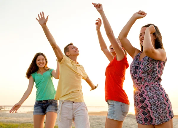 Amigos sonrientes bailando en la playa de verano — Foto de Stock