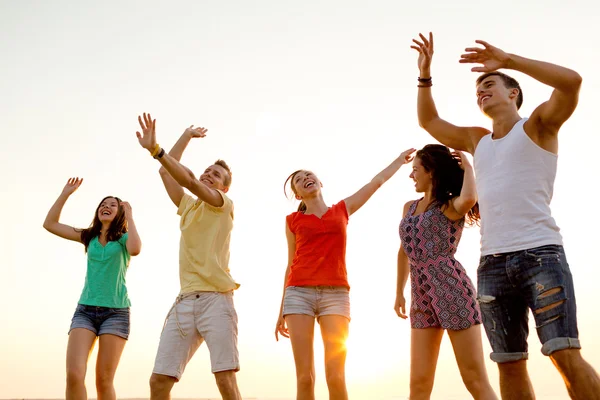 Amigos sonrientes bailando en la playa de verano — Foto de Stock