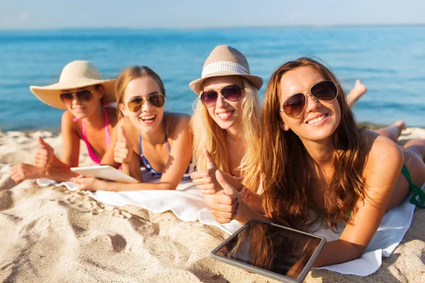 Grupo de mujeres jóvenes sonrientes con tabletas en la playa — Foto de Stock