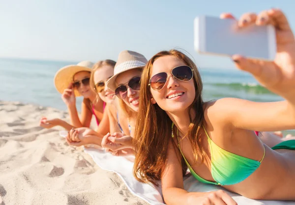 Groep van de lachende vrouw met smartphone op strand — Stockfoto