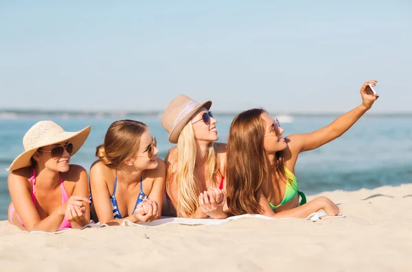 Groep van de lachende vrouw met smartphone op strand — Stockfoto