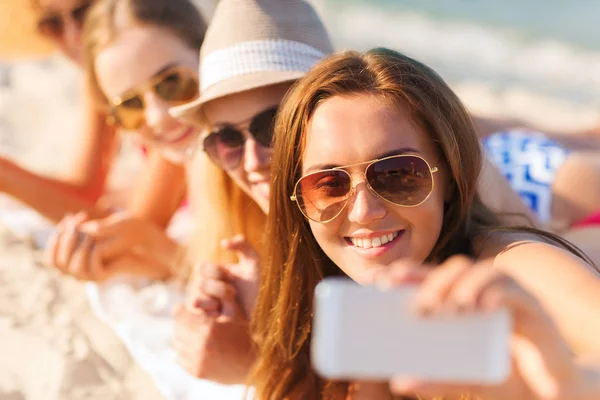 Primer plano de las mujeres sonrientes con teléfono inteligente en la playa Fotos de stock libres de derechos