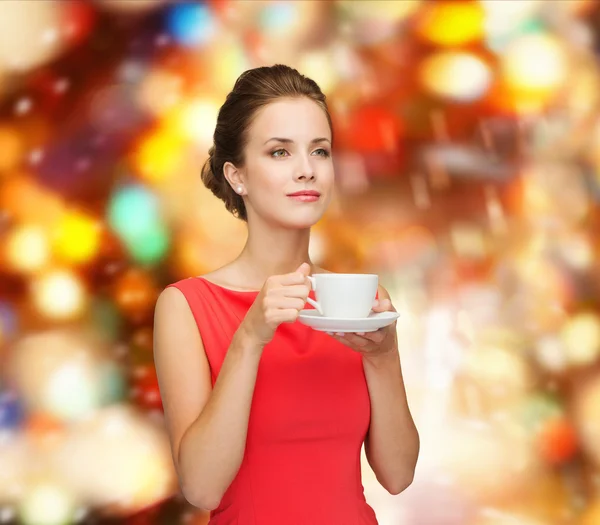 Lachende vrouw in rode jurk met kop koffie — Stockfoto