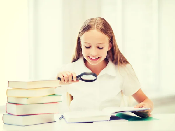 Mädchen liest Buch mit Lupe in der Schule — Stockfoto